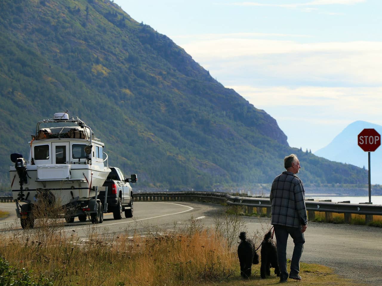 Pickup towing a fishing boat along a coastal mountain road
