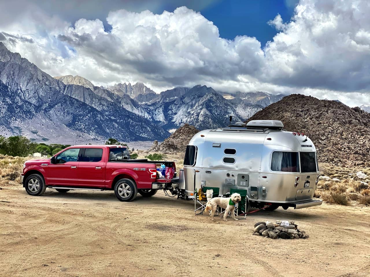 Red Ford F-150 hitched to a silver travel trailer at a desert campsite